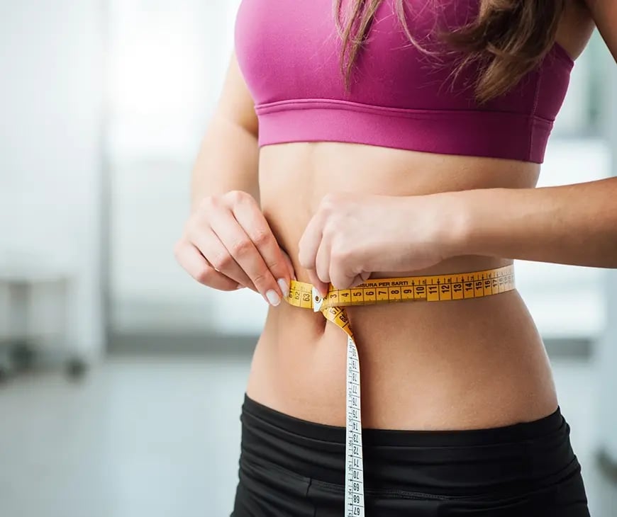 Woman measures her waist as part of her Weight Loss Program at Liquivida Wellness Center