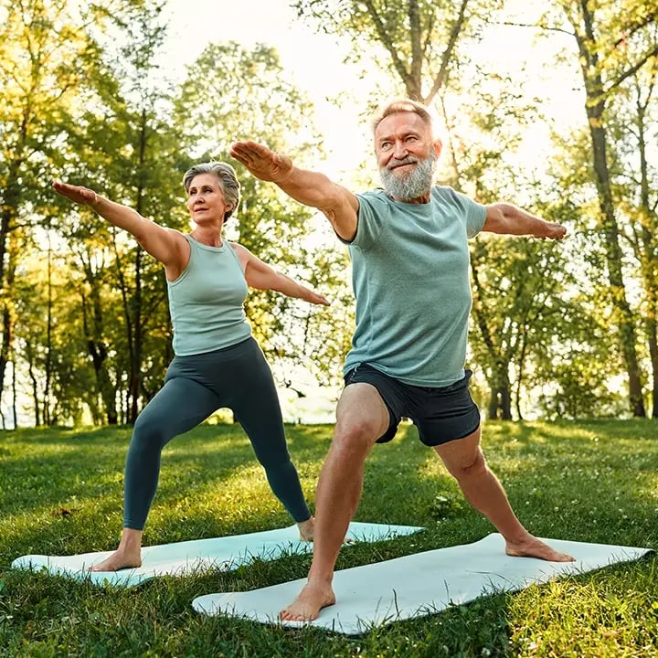 Old couple doing yoga in a park after getting Regenerative treatments at Liquivida Wellness Center