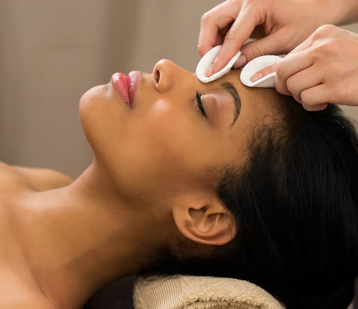 A beautiful black woman's face is being cleaned for a Chemical Peel at Liquivida