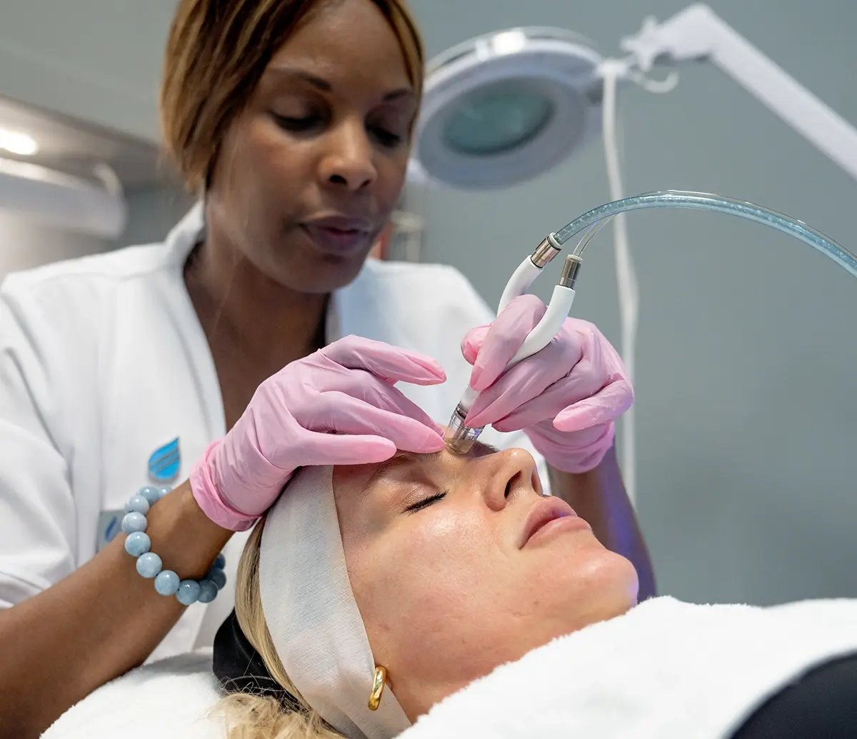 Practitioner doing a Diamond Glow on a white woman's face at Liquivida
