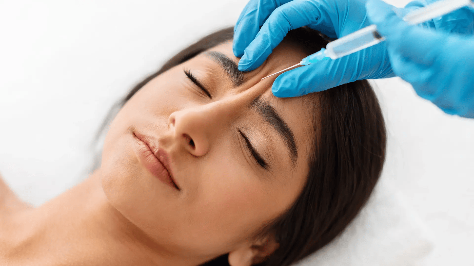 Woman with her forehead pinched by a practitioner while she gets a Dysport injection at Liquivida Wellness Center