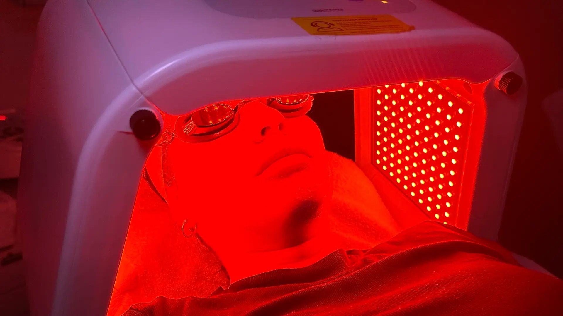 Woman's face with eyes covered inside of a Red Light Therapy device at Liquivida Wellness Center