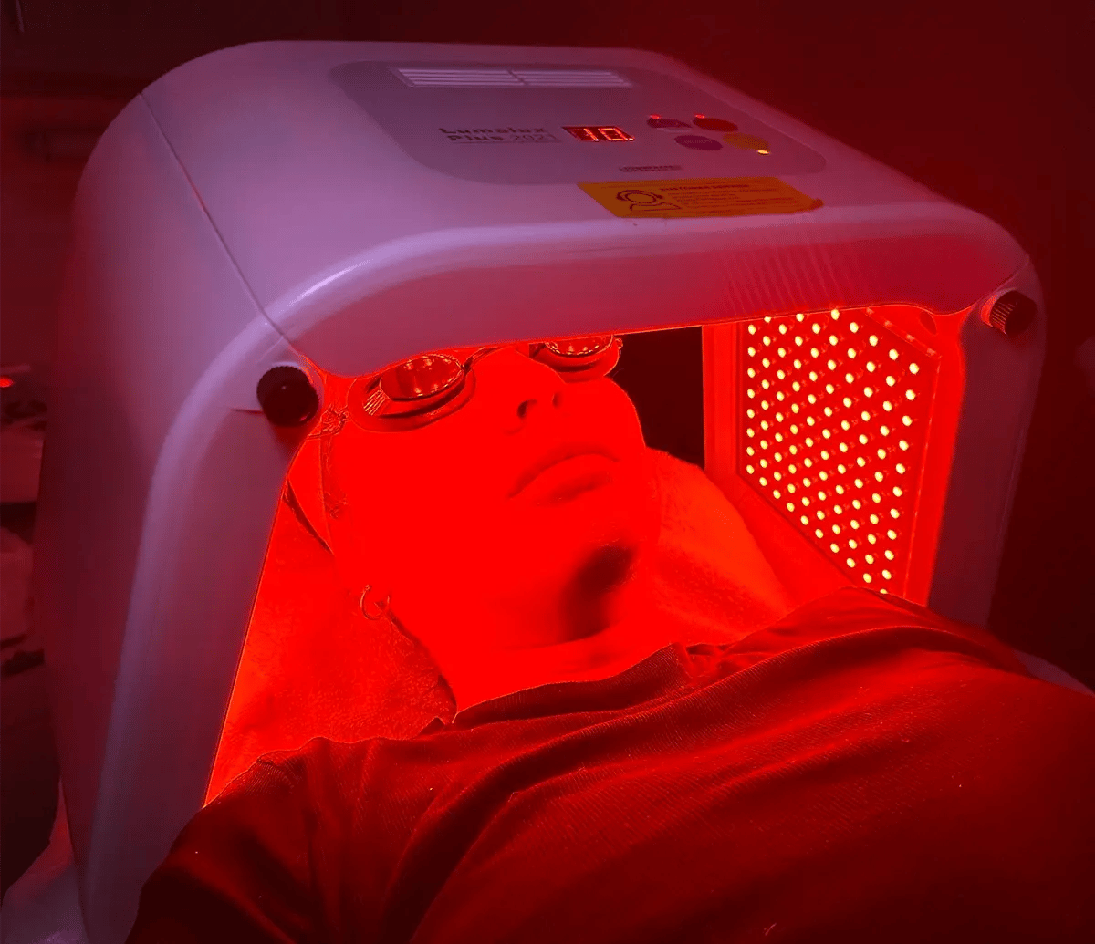 Woman's face with eyes covered inside of a Red Light Therapy device at Liquivida