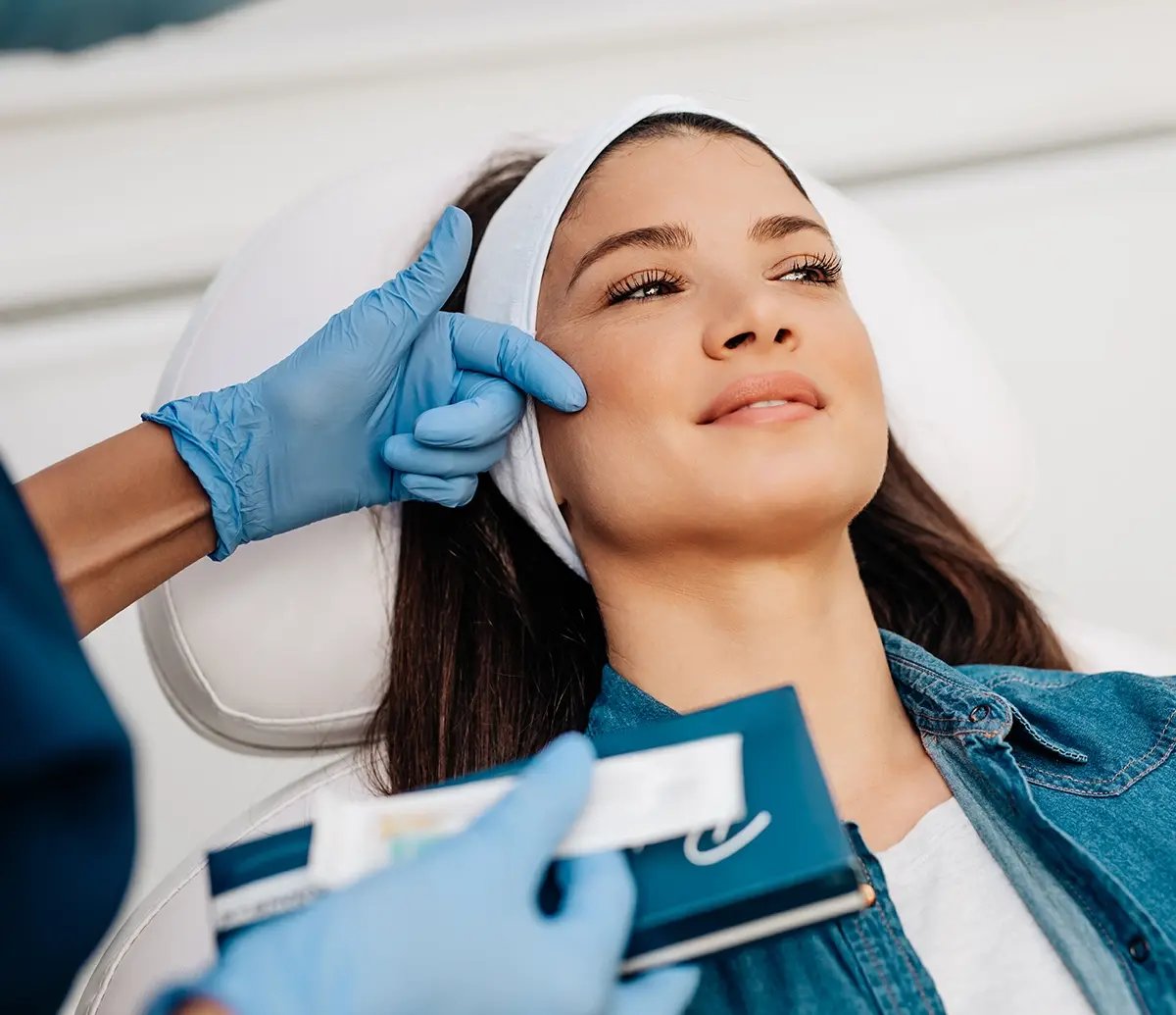 Practitioner evaluates the face of a woman before applying Restylane at Liquivida