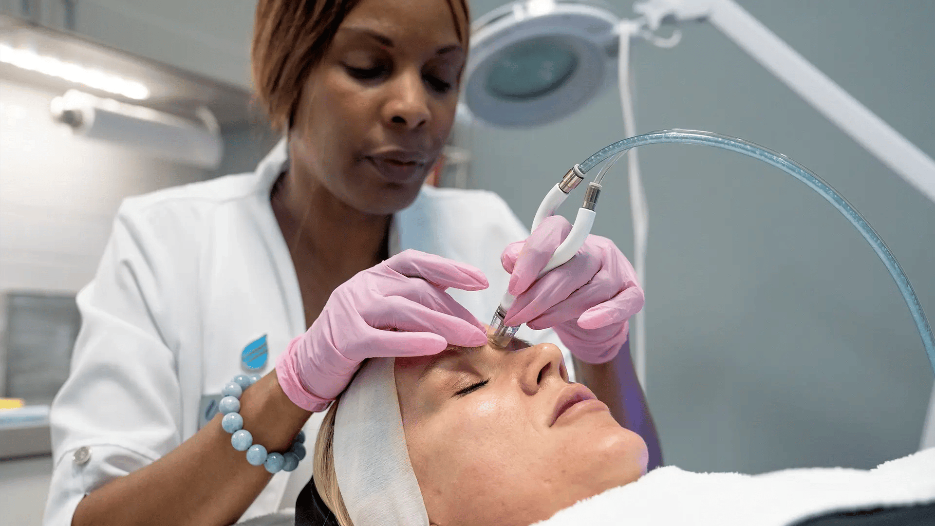 Practitioner doing a Diamond Glow on a white woman's face at Liquivida Wellness Center
