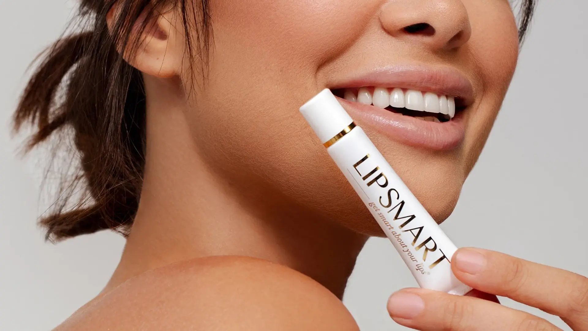 Happy woman holding a Lipsmart stick available at Liquivida Wellness Center