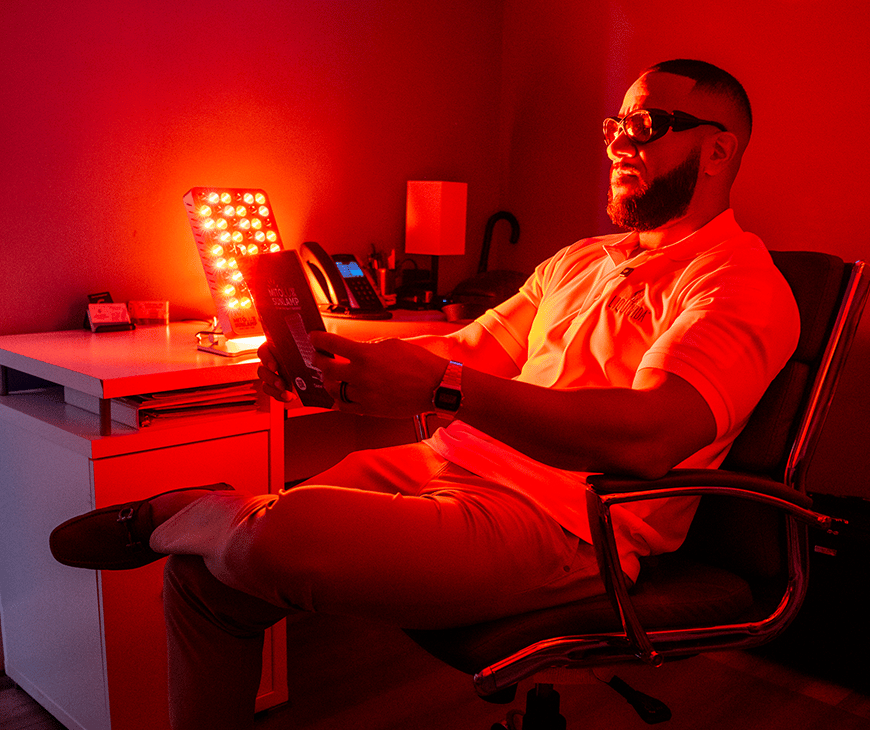Sam Tejada is reading in a red room while using a Mitolux Lamp at Liquivida