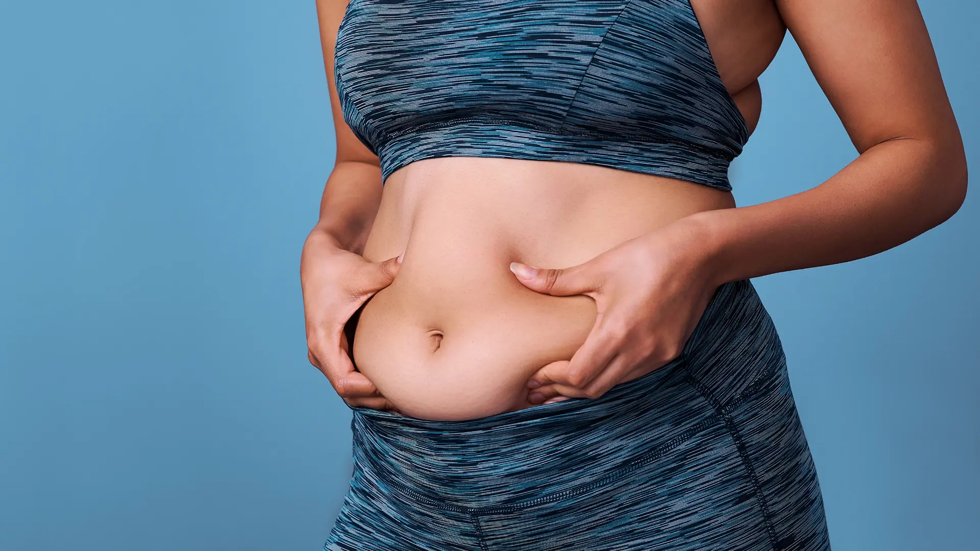 Woman pinching her belly before starting a GLP-1 weight loss program at Liquivida