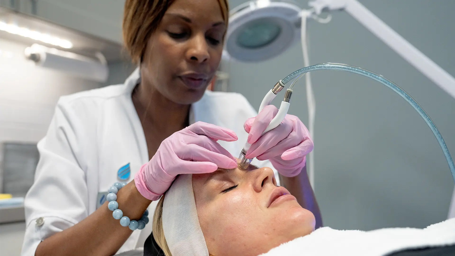 Practitioner doing a Diamond Glow on a white woman's face at Liquivida Wellness Center